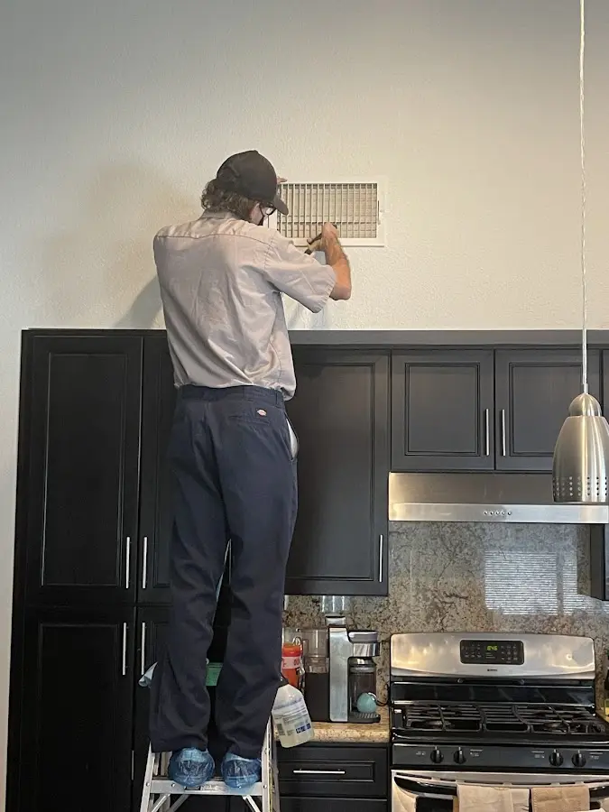 Technician inspecting an air vent during HVAC service in The Dalles